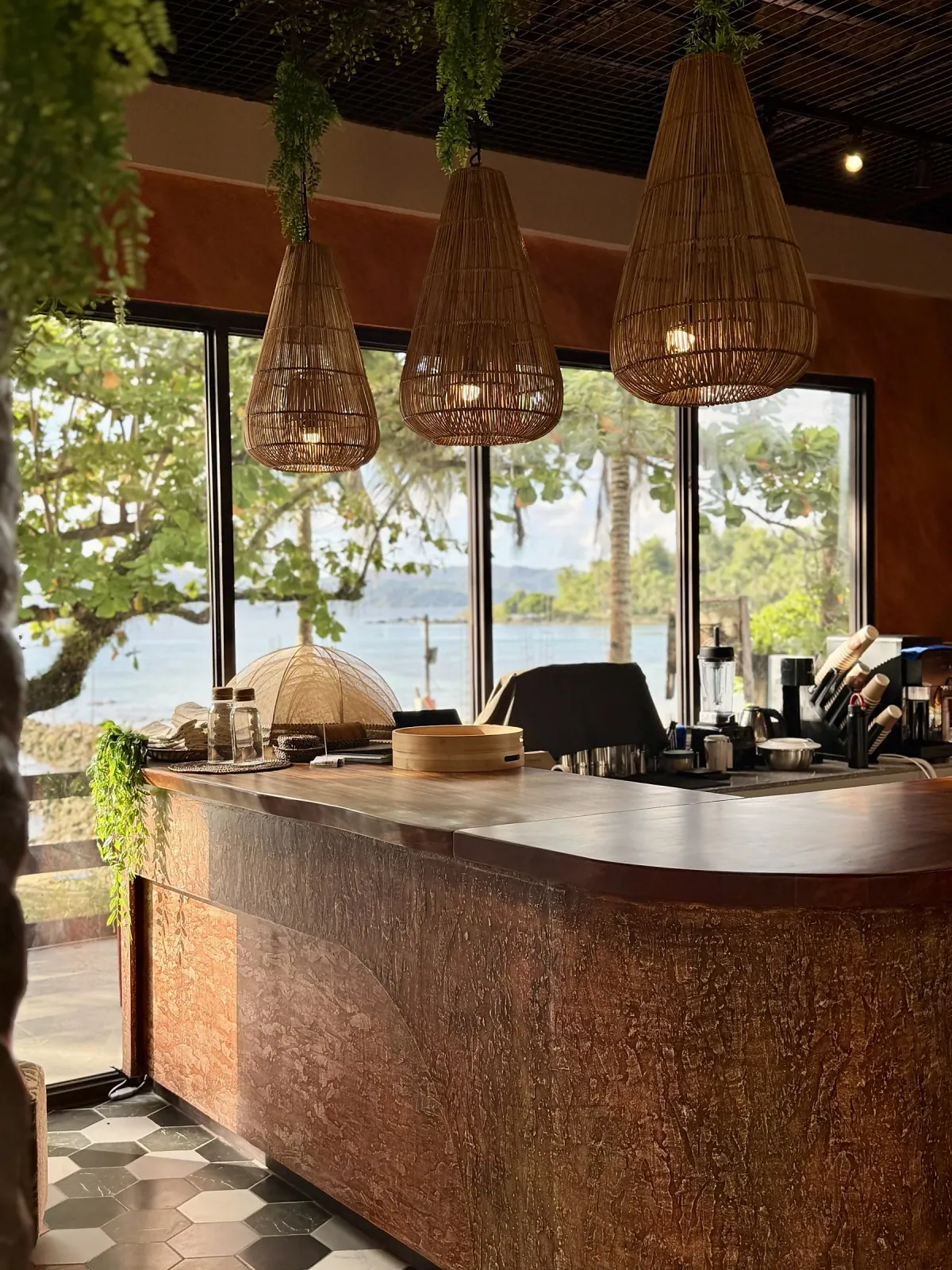 SANA bar counter with hanging rattan pendants and sea view through the windows