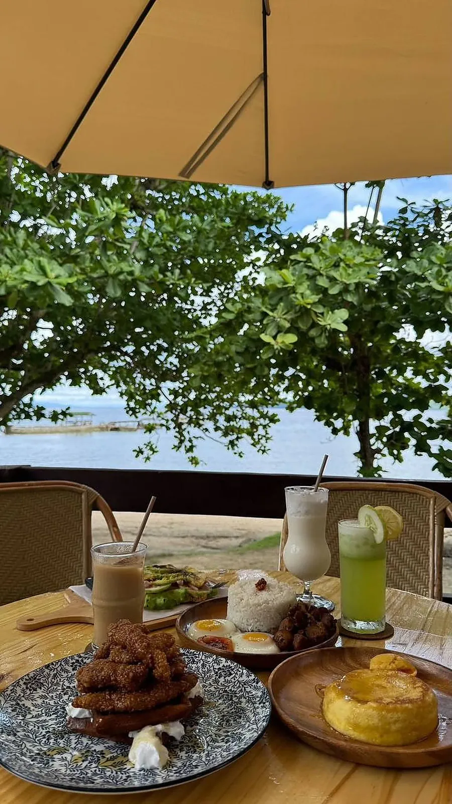 Beachfront breakfast spread under an umbrella with sea view