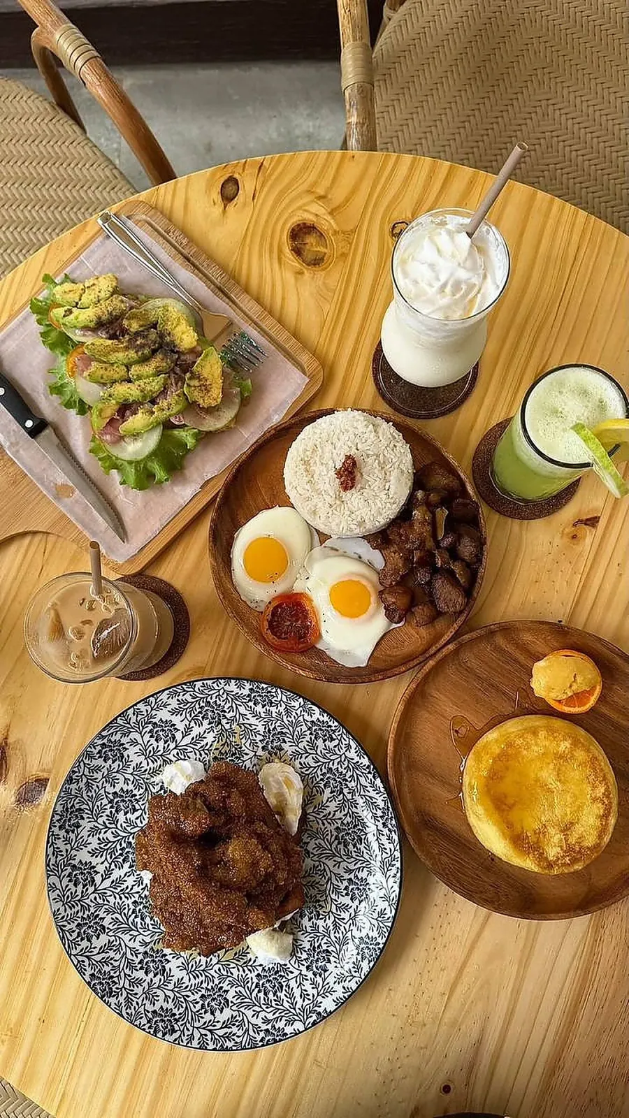 Top-down SANA brunch spread — avocado garden toast, a comfort meal with eggs and garlic rice, and a maple butter soufflé