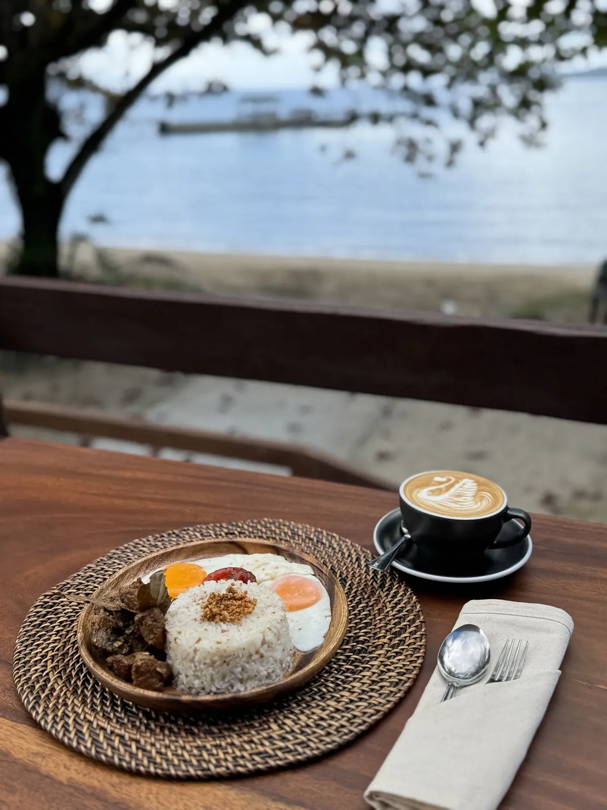 A SANA comfort meal with two eggs and garlic rice, paired with a cappuccino by the sea